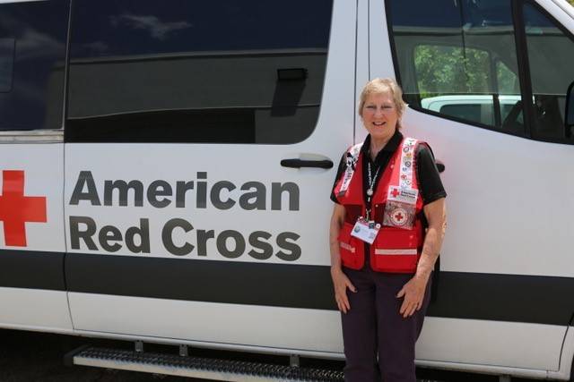 A person standing next to a white van with a red cross symbol