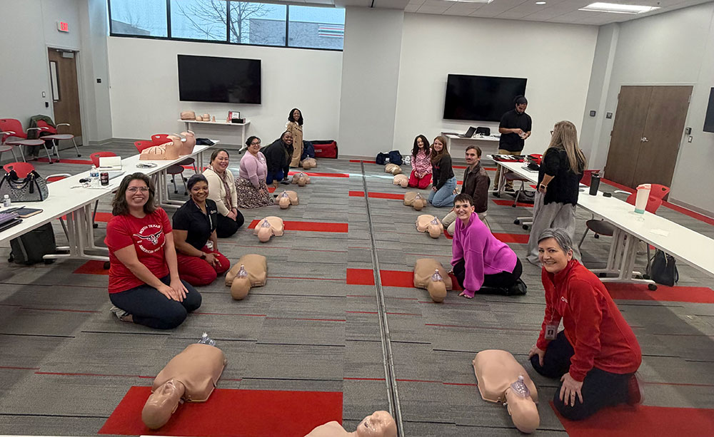 A Red Cross cpr training classroom with people training on manikins.