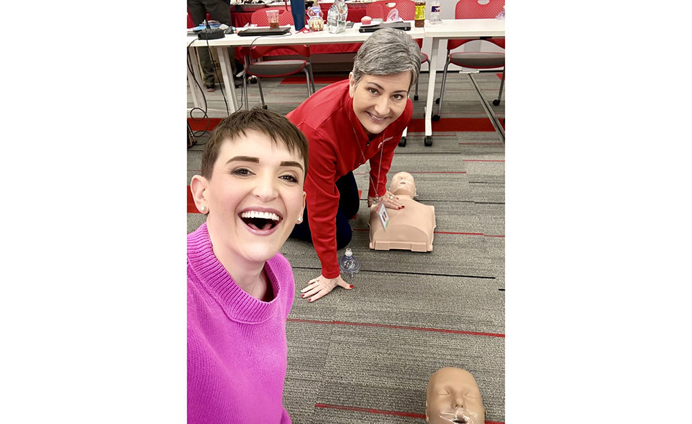 Dallas Caulkins and a Red Cross staff member training on CPR manikins.
