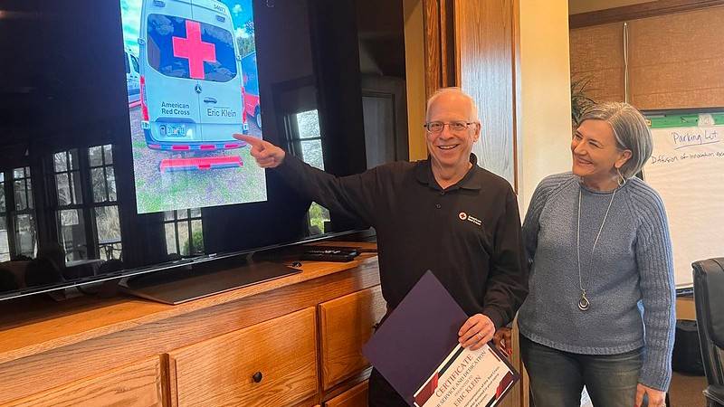 Standing with Red Cross North Texas CEO Linda Braddy, Red Cross volunteer Eric Klein sees a picture of the ERV honoring him for the first time. 