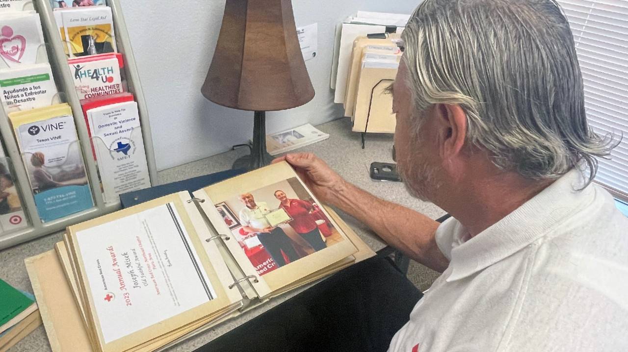 Joseph Misek, a 52 year Red Cross volunteer reviews his memory book.
