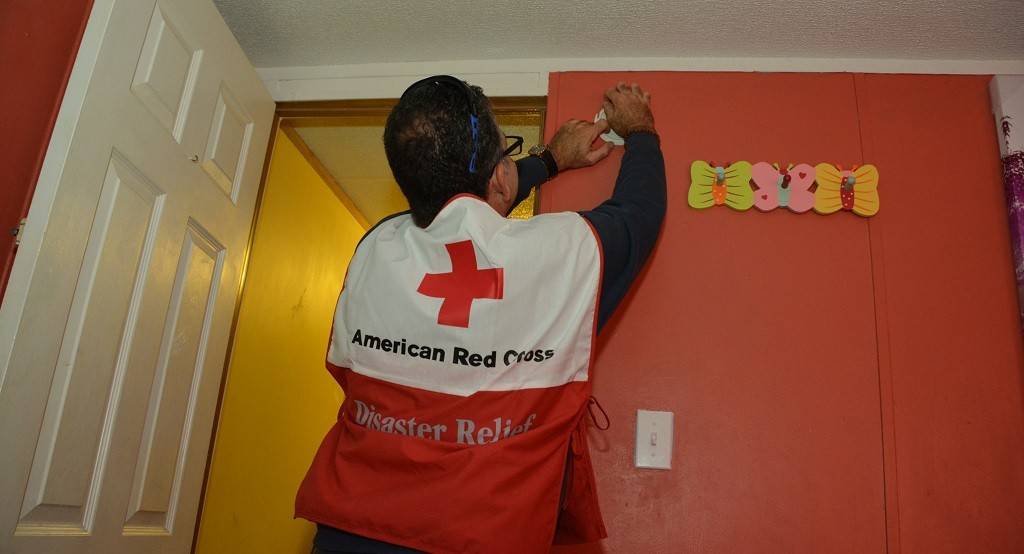 Red Cross volunteer installs a smoke alarm in a home