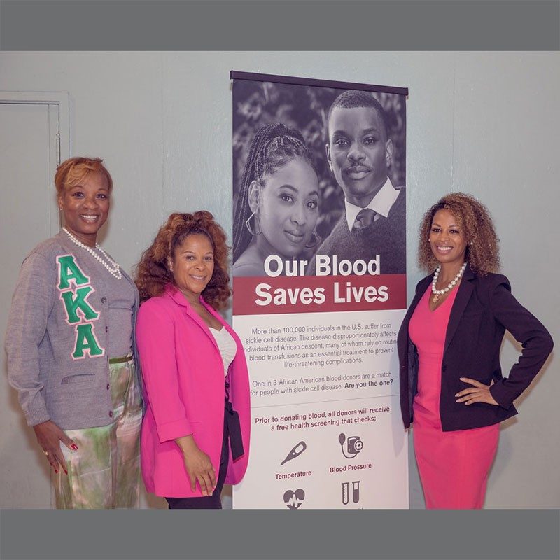 Three women next to Our Blood Saves Lives banner.