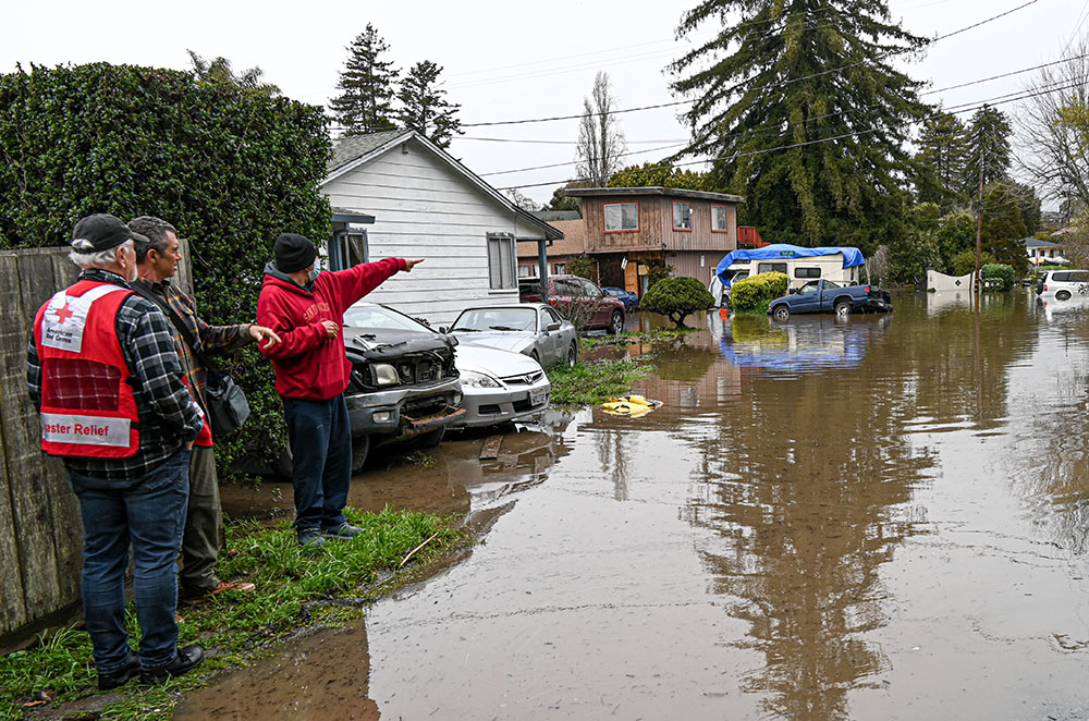 Red Cross volunteers look at flooding in residential area.