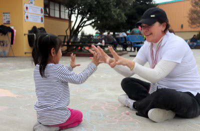 Red Cross volunteer sitting with child and playing.