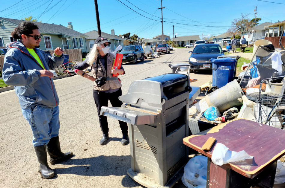 Simon Mata showing American Red Cross volunteer Barbara Wood the huge pile of muddy garbage in front of his home.