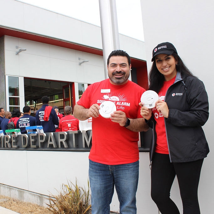 Red Cross volunteers holding smoke alarms.