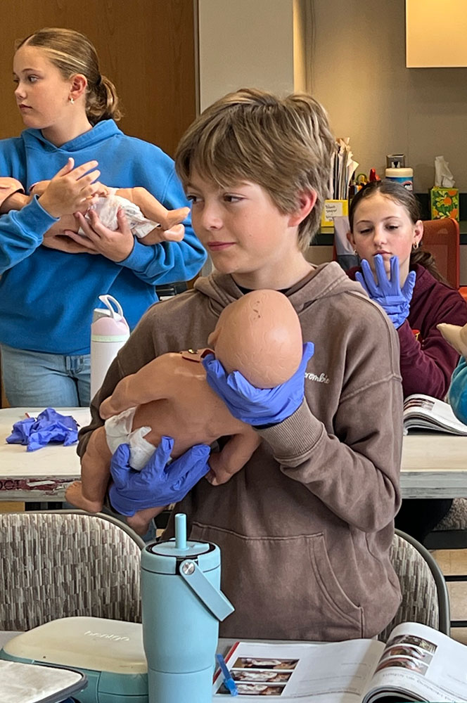 Molly Foster, Trey Roost and Eloise Green practice holding and feeding mannequin babies.