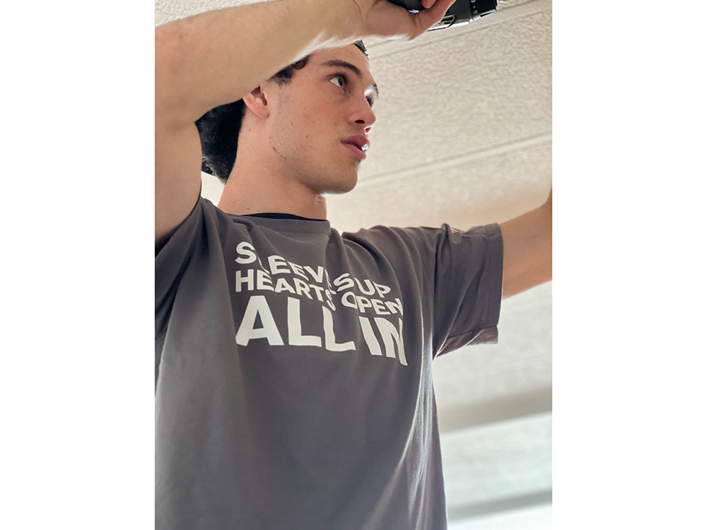 Red Cross volunteers Brayden Rapa installing a smoke alarm.