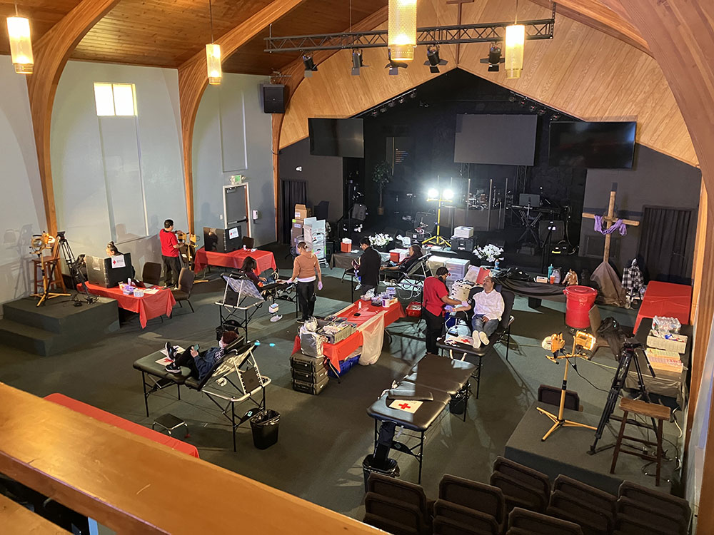 Room full of Red Cross nurses, cots, and volunteers donating blood