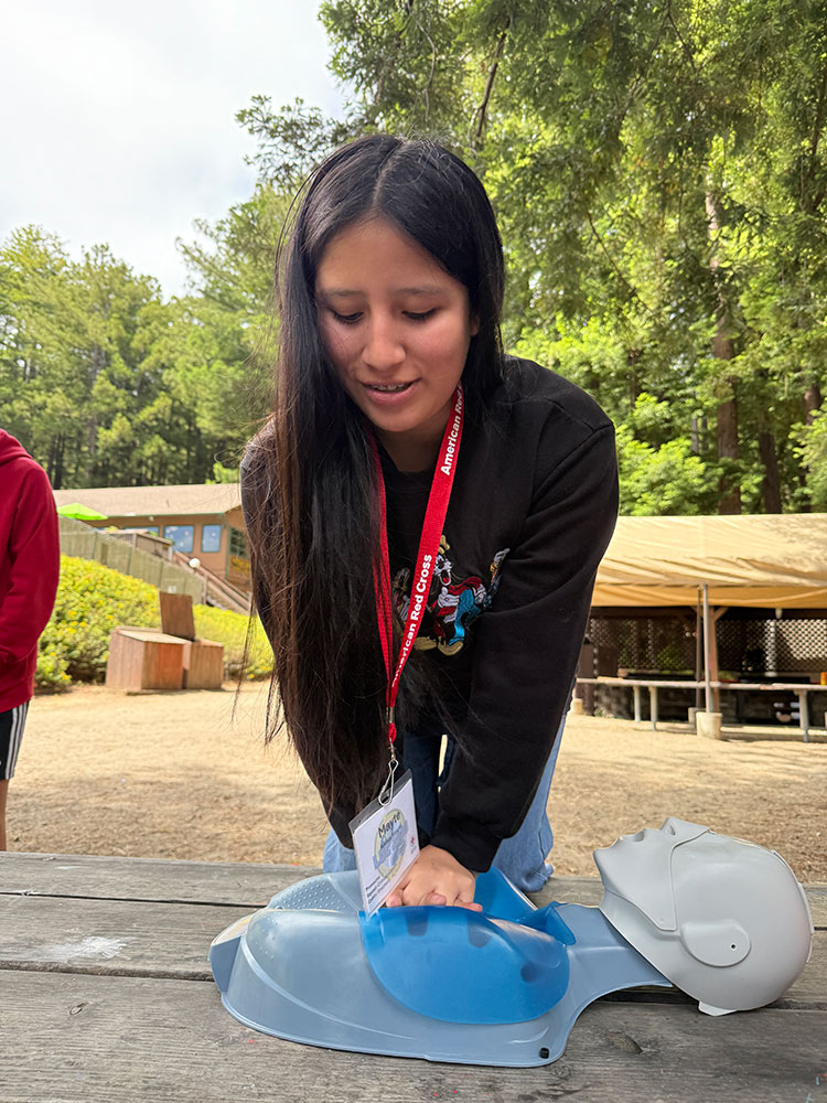 Mayte Yangali practicing CPR outside on a manikin.