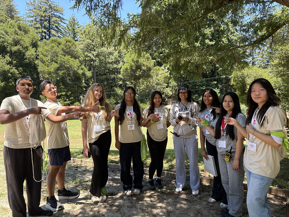 A group photo of the Red Cross camp leaders under the shade of a tree.
