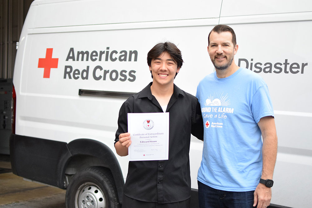 Edward Kuan holding the Red Cross Certificate of Extraordinary Personal Action with regional ceo justin mueller next to him.