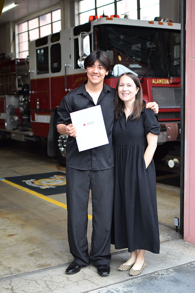 Edward Kuan holding the Red Cross Certificate of Extraordinary Personal Action with his nominator, Christy Trombley, next to him.