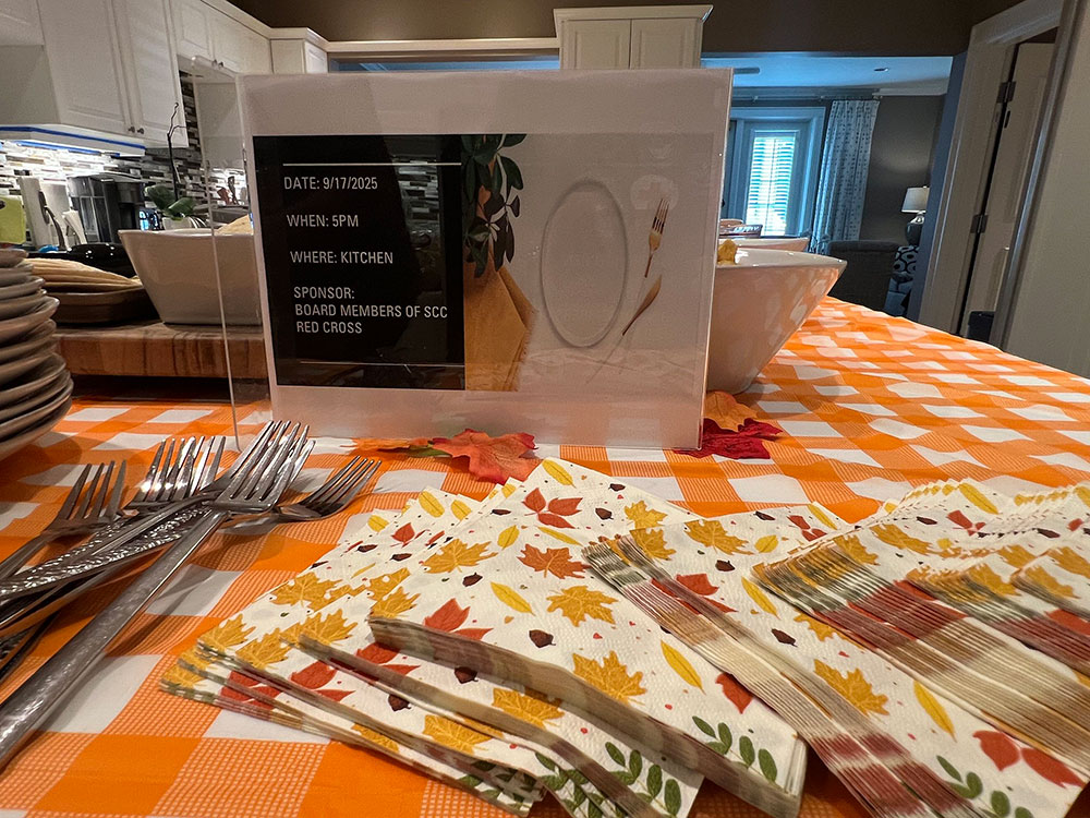 an event sign on a table with forks, napkins, and plates.