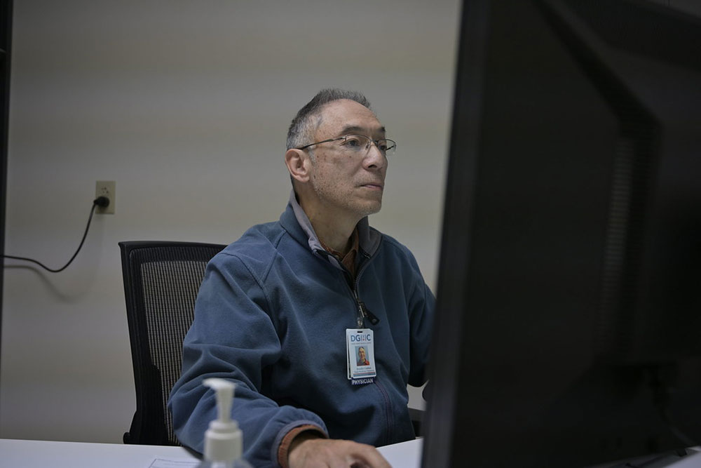 Dr. Dan Canlas working at a desk on a computer.