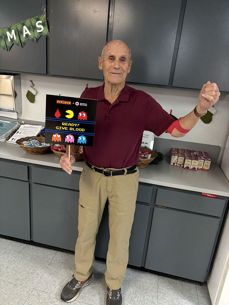 Fred Sullivan at the Pleasant Hill Blood Center holding a PACMAN promotion sign.