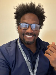 Gerald Golstein wearing reading glasses and a lanyard while smiling for picture.