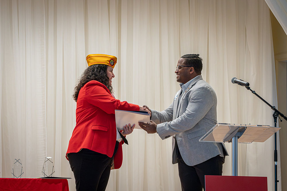 Gerald Golstein handing an award and shaking the hand of another person at a Red Cross event.