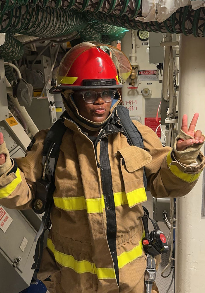 person in a fire fighters gear giving a peace sign.