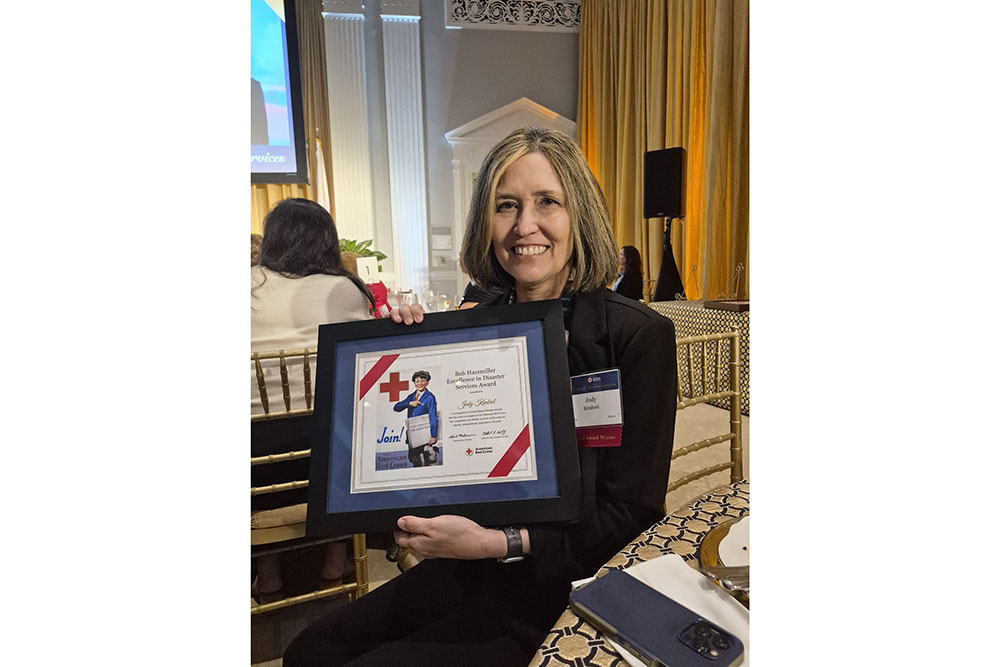 Jody Kimbrel smiling while holding a framed Red Cross award.
