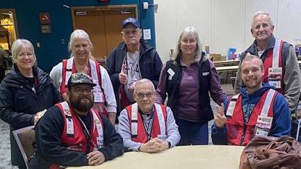 group picture of Laura Hovden and other red cross volunteers in a room sitting at a table.