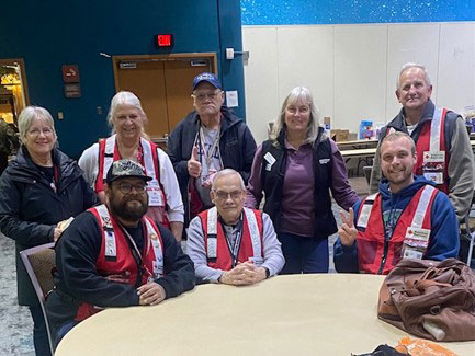 group picture of Laura Hovden and other red cross volunteers in a room sitting at a table.