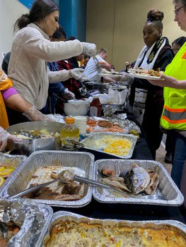 red cross volunteers serving food to shelter residents.