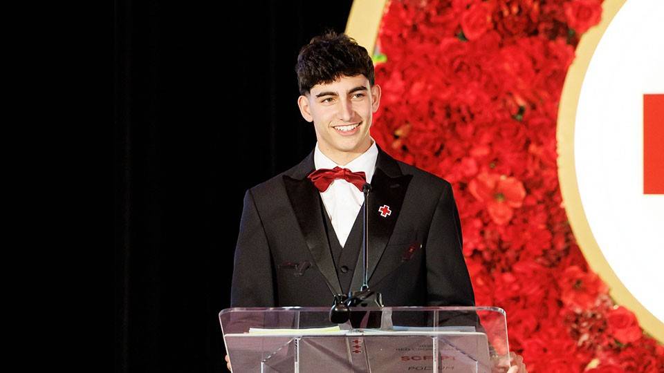 Malik Osman, in suit and bow tie, at a podium accepting his Lifesaving Award at the 2026 Red Cross Gala.