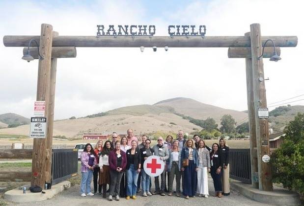 Group of people posing fpr a picture holding red cross sign