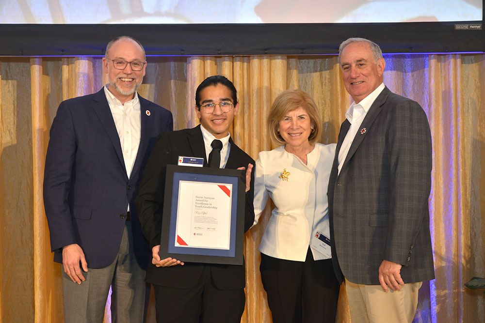 Razi Aftab, holding a Red Cross award, and three other people, in dress clothing, at a Red Cross event.