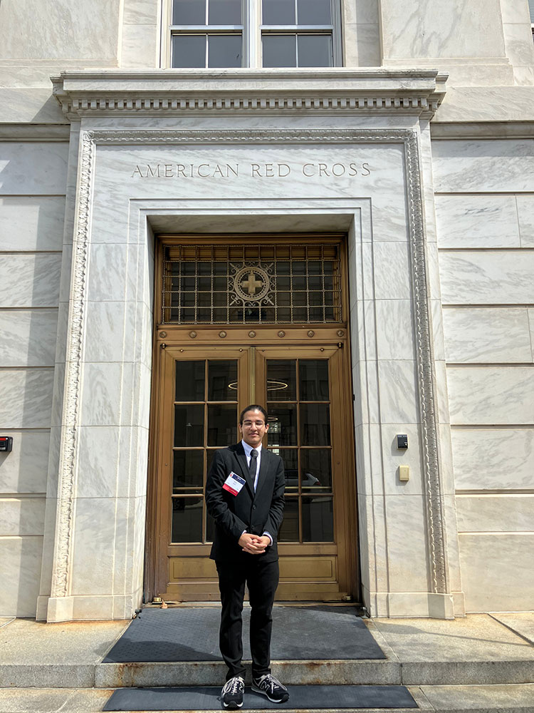 Razi Aftab stands in front of the American Red Cross building entrance in Washington, DC.