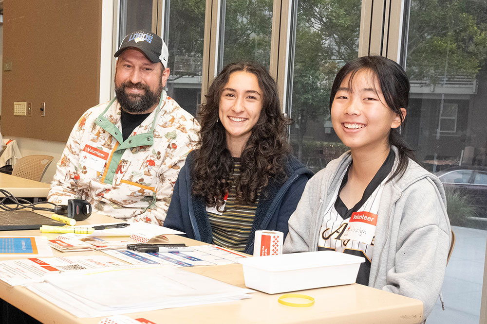 Spencer Archer and two of his 8th grade students sitting at a table and smiling for picture.