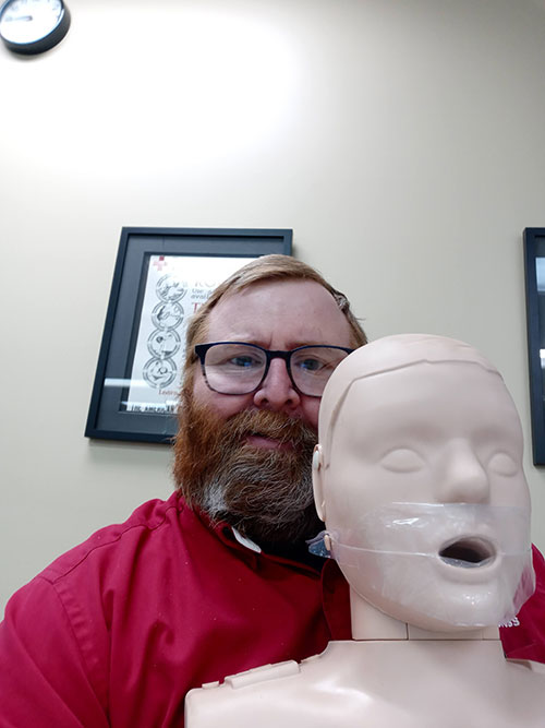 Steven Bradley poses for picture while holding a CPR Manikin.