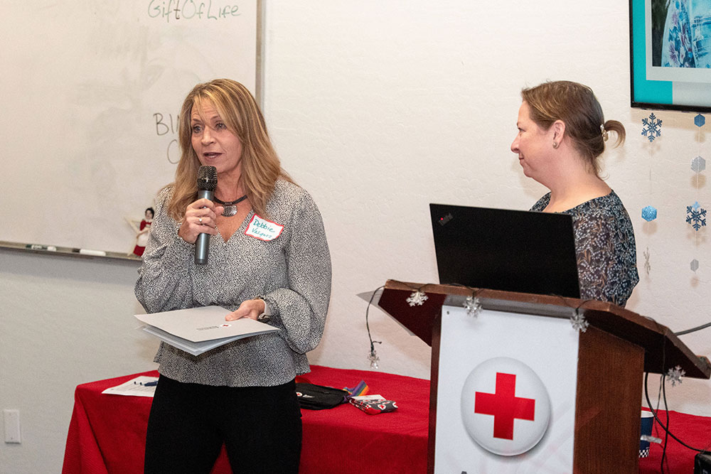 Debbie speaking on a mic at the Lifesaving Award ceremony.