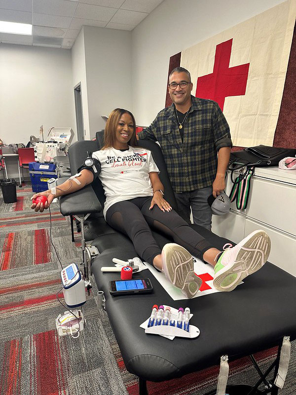 Nichole Jordan sitting in chair dontating blood with Ed Faso next to her.