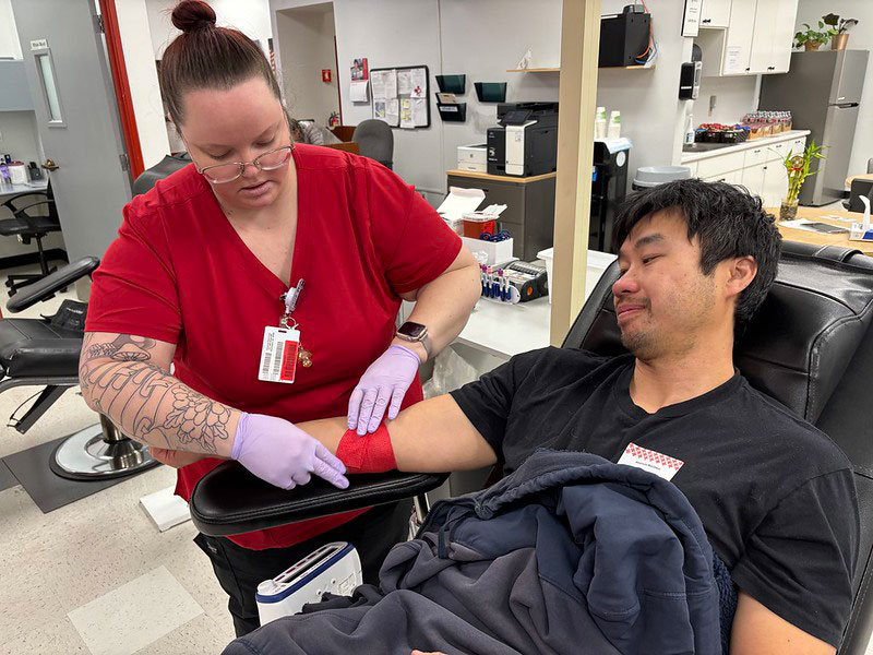 Red Cross nurse wrapping Hayes Shair's arm after donating blood.
