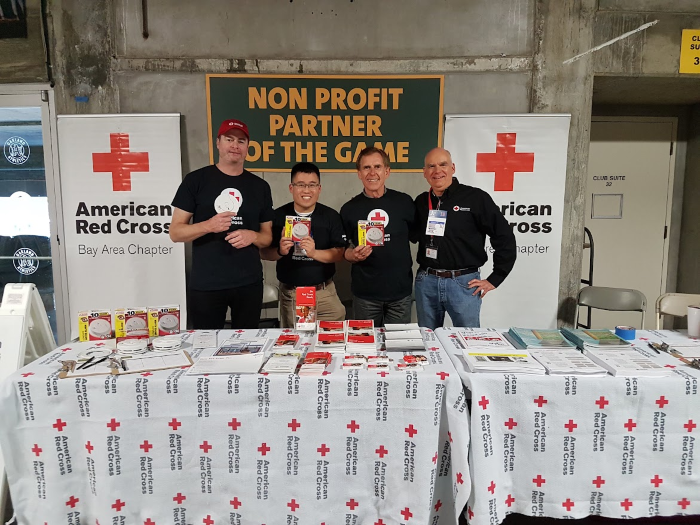 Photo of John Earthy and other Red Cross volunteers at an event table.