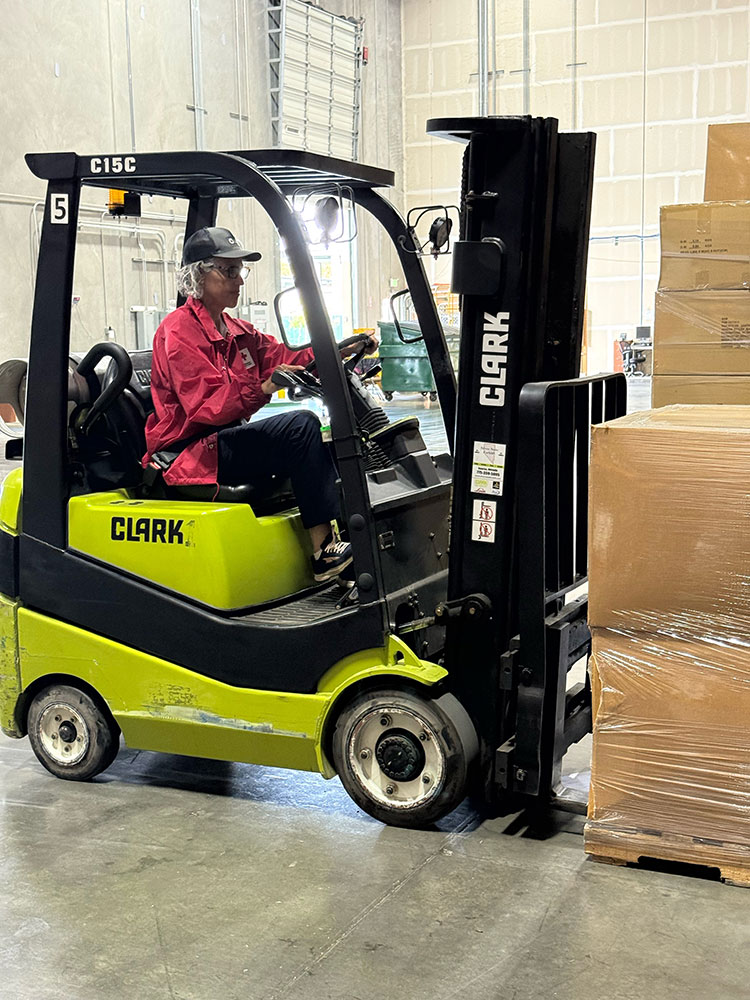 Lyra Kelly driving a forklift in order to get supplies delivered to families in need.