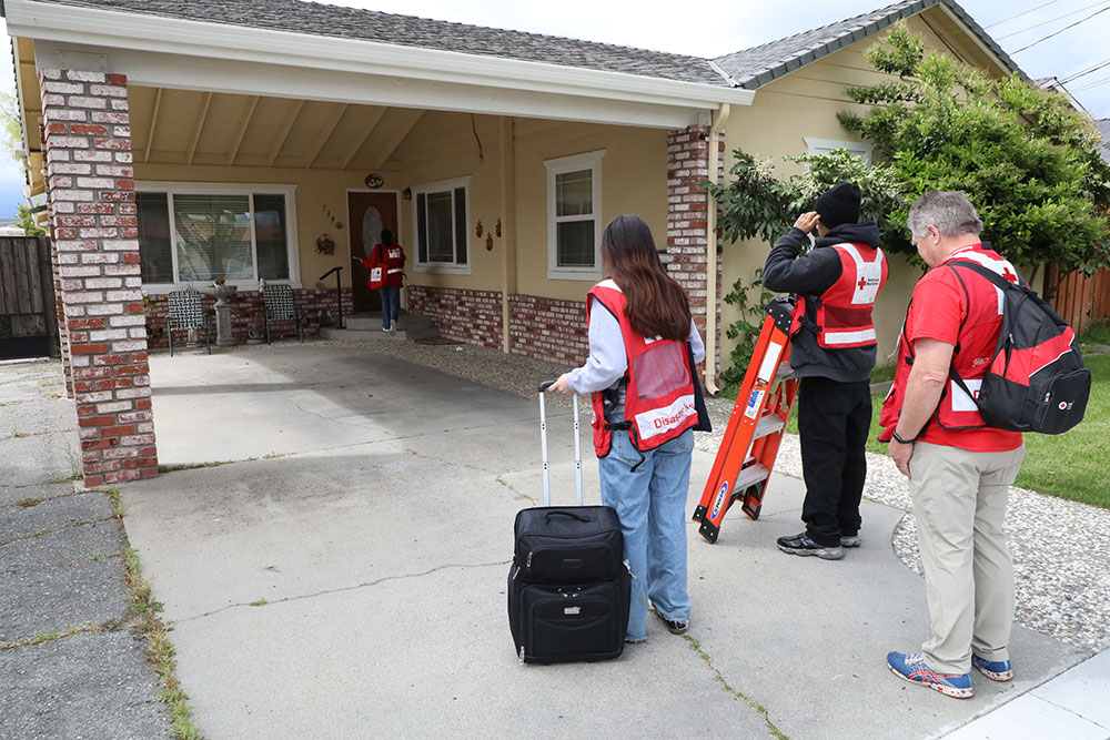 Red Cross volunteers at the front door of a house ready to install smoke alarrms.