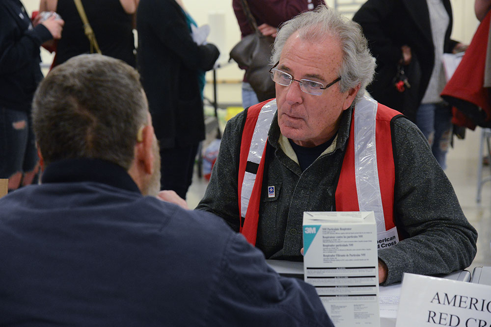 Red Cross volunteer sitting at table and helping a disaster victim.