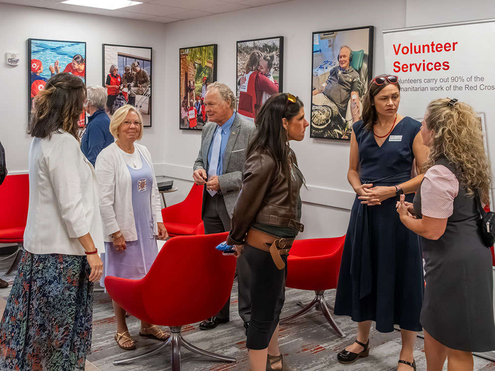 people standing and talking in the newly renovated Red Cross facility in Portland, with chairs and pictures on the wall.