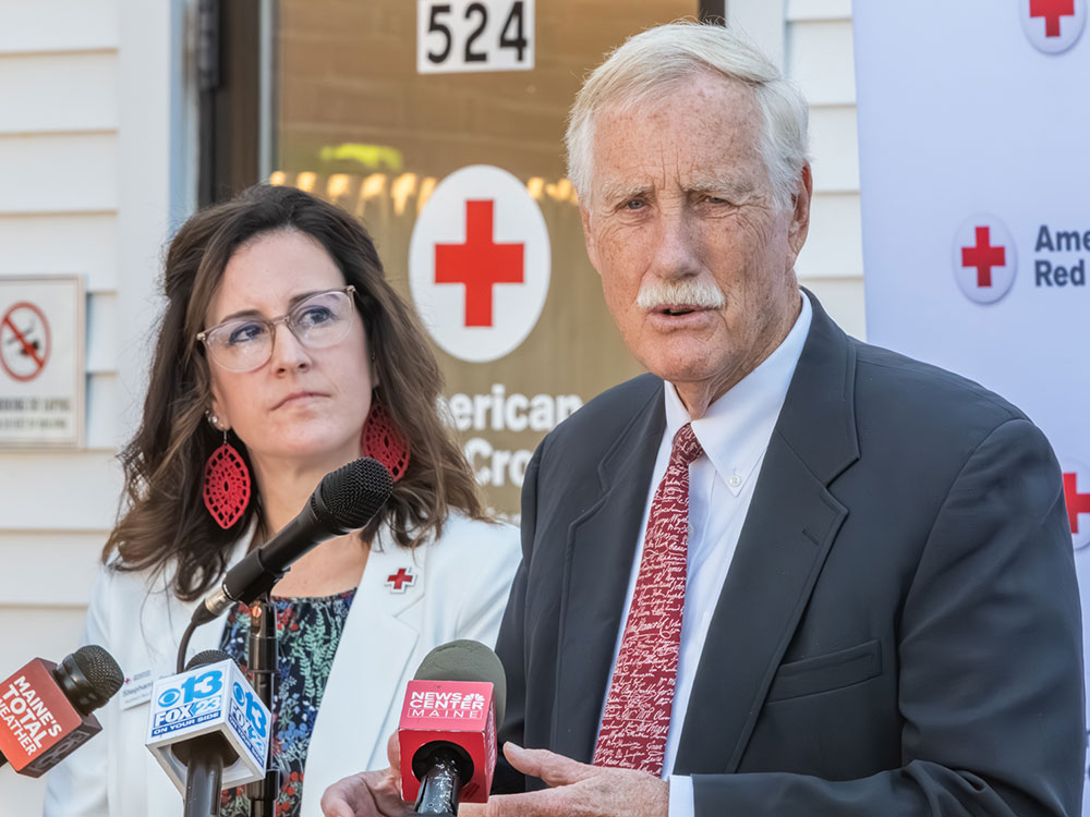 two people standing at podium with one speaking on a microphone.