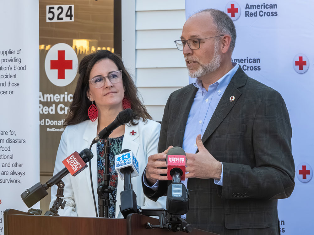 two people at podium with one speaking on a microphone.