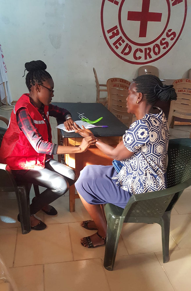 Red Cross volunteer Chinenye Angela Okoli and another person sitting at table and looking at paperwork.