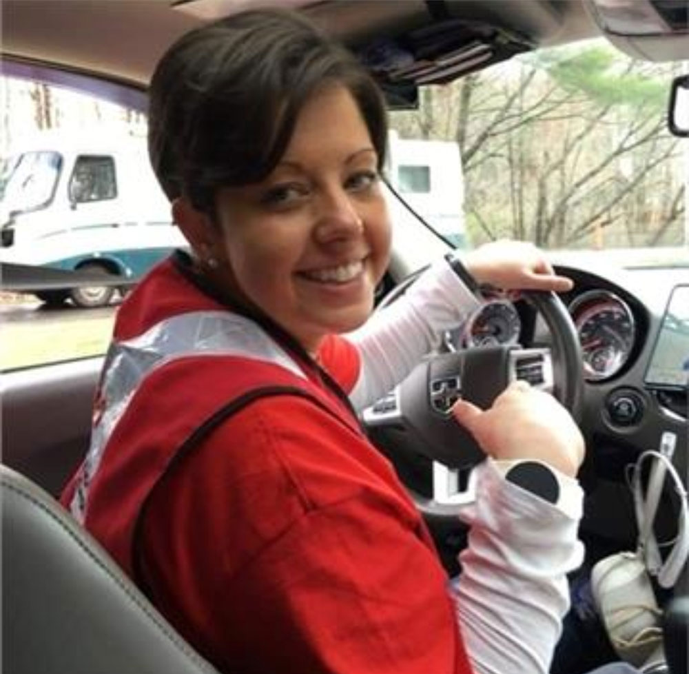 Ashley St. Louis inside a car while wearing a Red Cross shirt and safety vest.