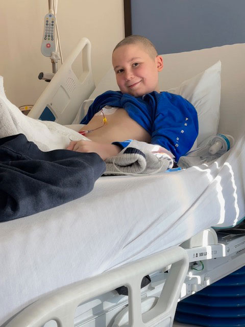 Avery MacNair lying on hospital bed and smiling
