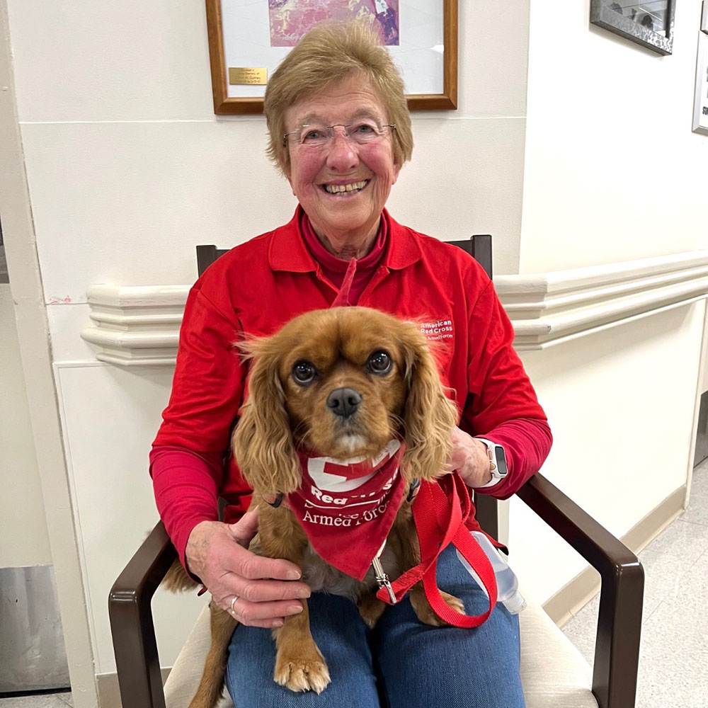 Barbara Desjardins and therapy dog Gracie sitting in a chair.