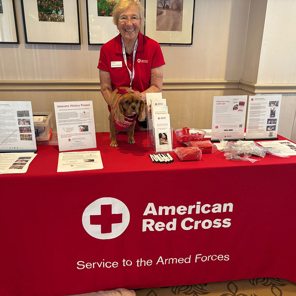 Barbara Desjardins and therapy dog Gracie working at a Red Cross Service to the Armed Forces Therapy Team booth.