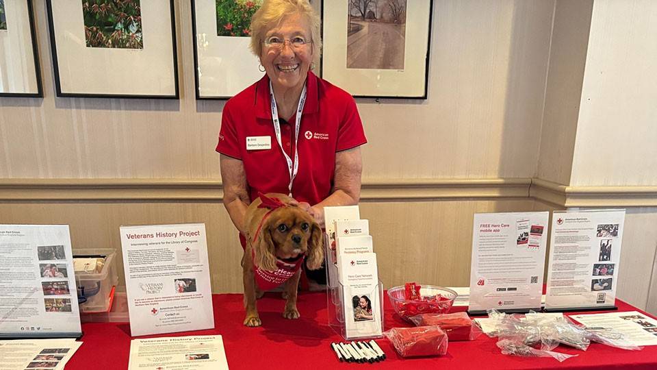 Barbara Desjardins and therapy dog Gracie working at a Red Cross Service to the Armed Forces Therapy Team booth.